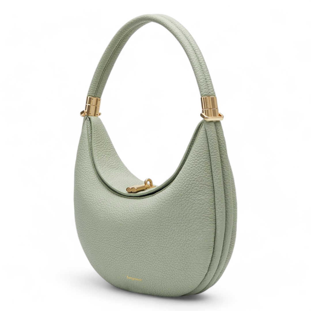 Un bolso de mano de cuero en color verde menta, con un diseño curvado y un asa semicircular dorada. El cierre del bolso es dorado, y tiene un acabado texturizado.